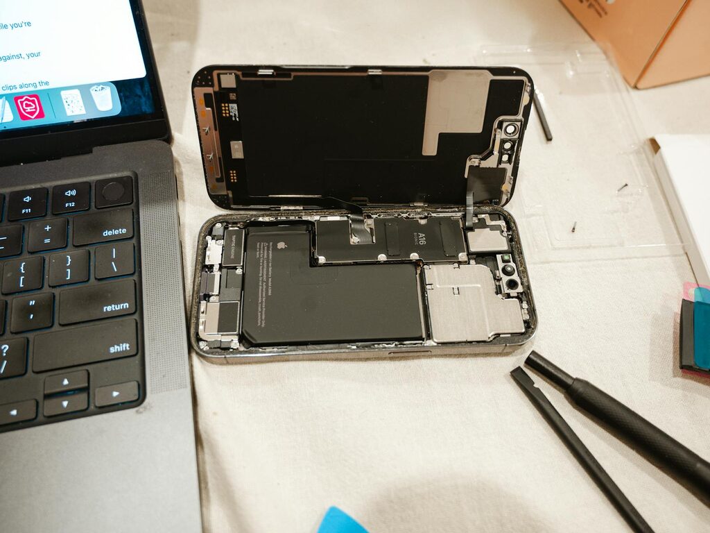 Open phone with battery exposed and repair tools laid out