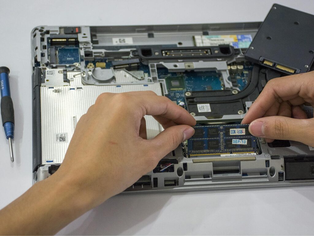 A hand fixing the internal parts of a laptop