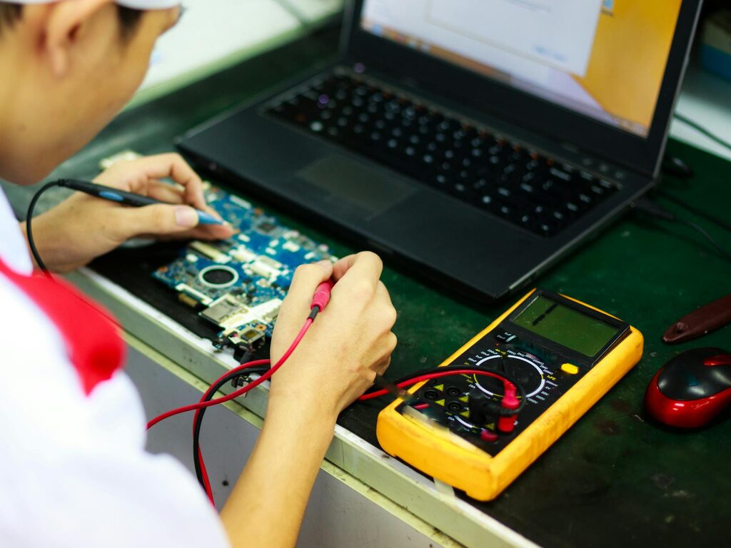 Technician soldering a laptop logic board at the workbench