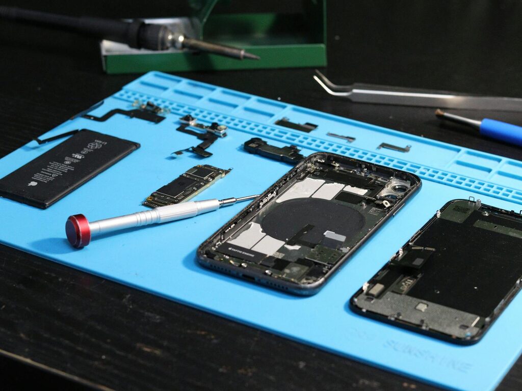 Disassembled Samsung smartphone with the back glass removed on a repair workbench
