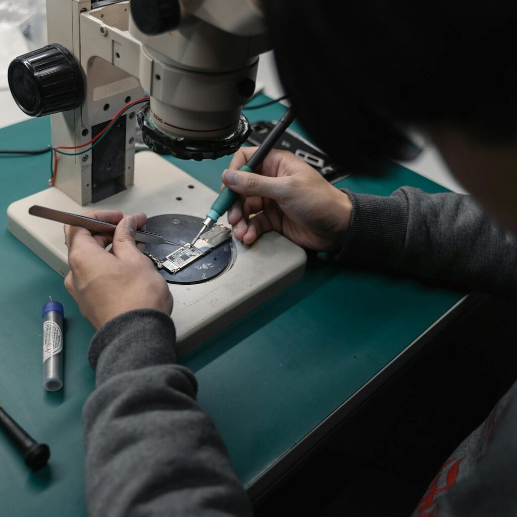 Technician inspecting a circuit board through a microscope