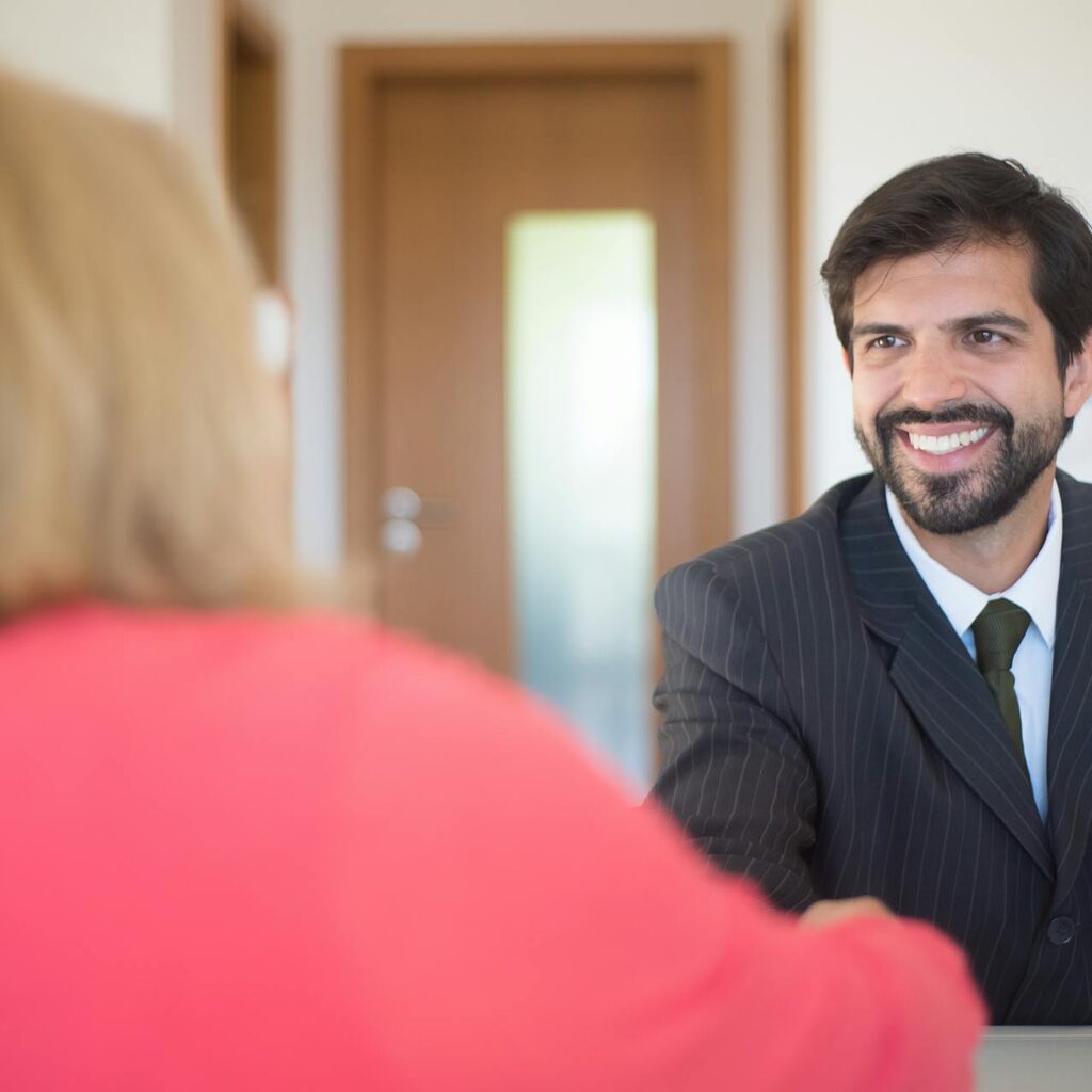 Smiling man in a black suit shaking hands with a customer